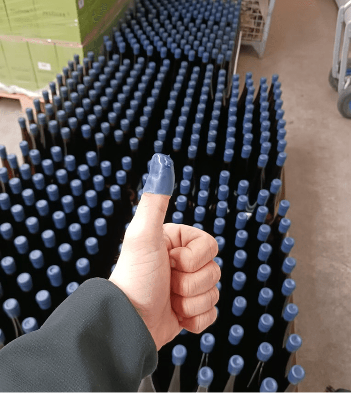 Tommel opp, vin i bakgrunnen